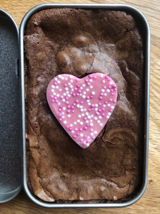 Letterbox friendly heart topped brownie in a tin with wooden spoon